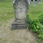 A grave with a stone headstone accompanied by a small tree, evoking a sense of serenity and reflection